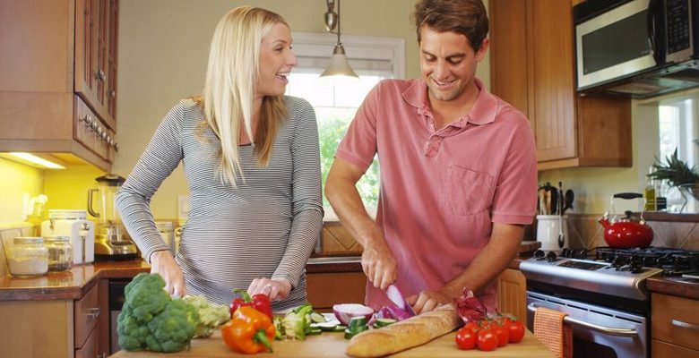 Casal preparando alimento para dieta na gravidez. Dieta para grávida.