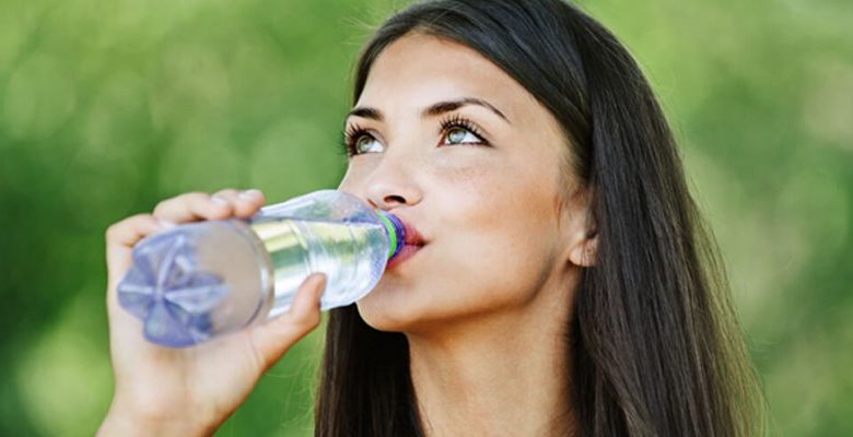 Mulher tomando água, hábitos saudáveis.