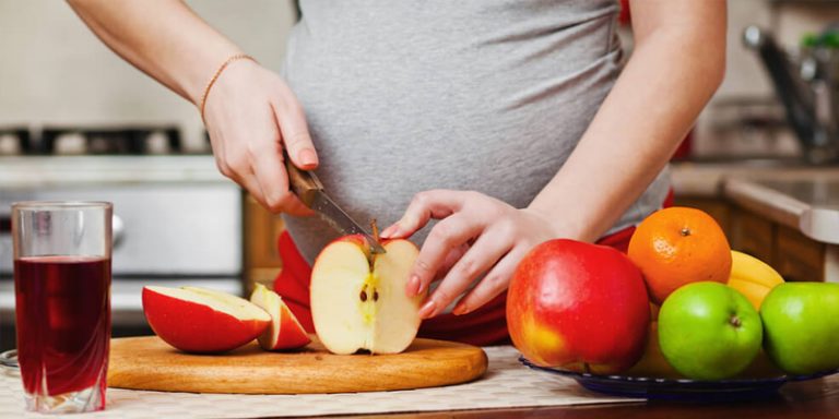 gestante cortando mação para manter alimentação saudável