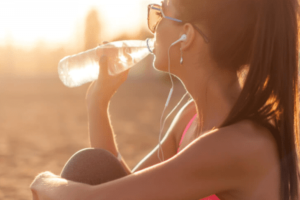 mulher se hidratando bebendo água tarde ensolarada exercícios