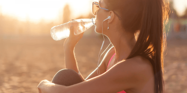 mulher se hidratando bebendo água tarde ensolarada exercícios