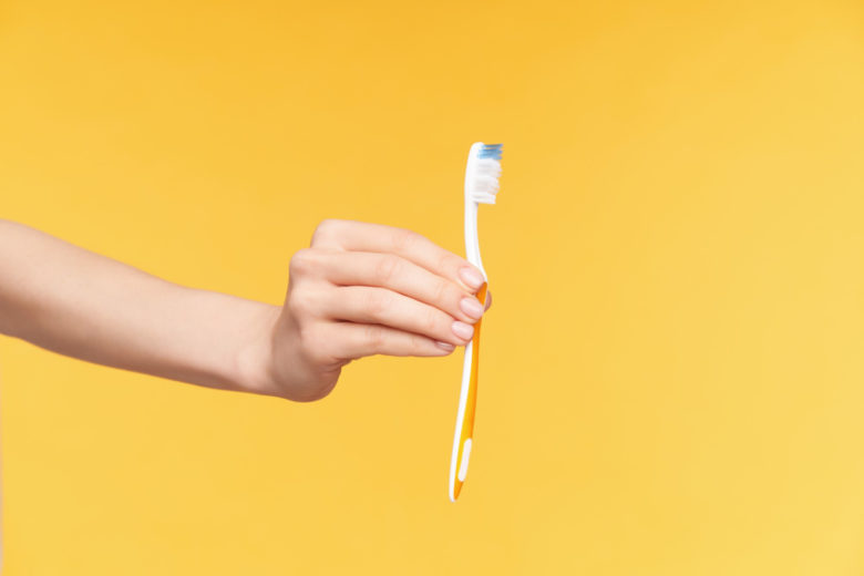 foto de mão segurando escova de dente demonstrando melhor escova de dente na clínica sim