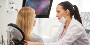 dentista-conversando-com-mulher-preocupada-durante-exame-dentario