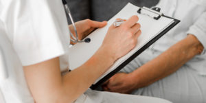 Médico realiza exames de rotina em paciente e anota resultados
