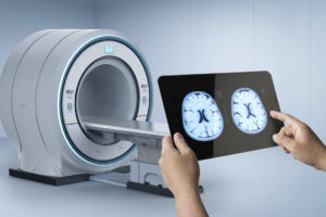 Médico segura resultado de exame de imagem em frente à uma máquina de ressonância magnética
