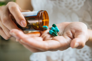 Mão de mulher derrama as pílulas de antibióticos fora da garrafa